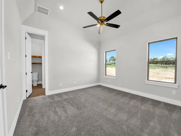 an empty room with windows and fan