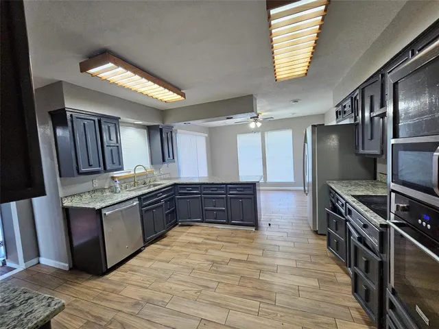 an empty room with wooden floor chandelier fan and windows