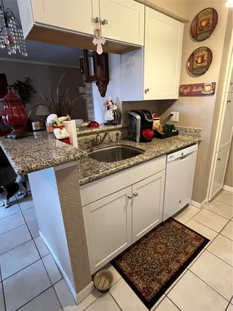 a kitchen with granite countertop a sink a stove and cabinets