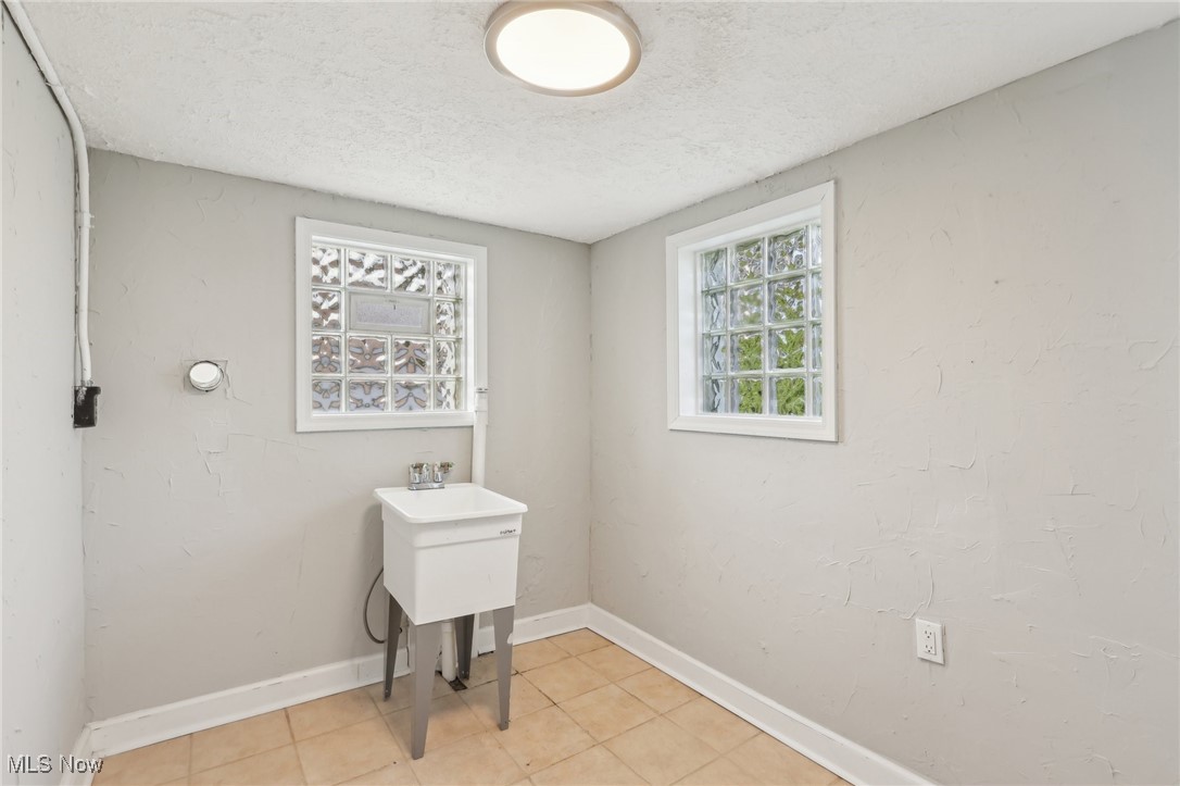 9273 Roxbury Road Parma Heights, OH 44130 - Photo 14 of 27 Laundry area featuring light tile patterned floors, a textured ceiling, and baseboards