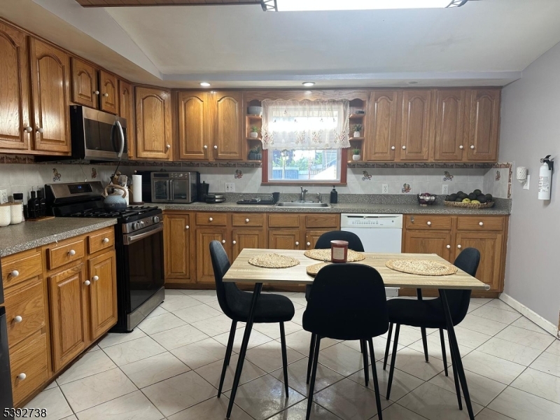 828 Allen Street Linden, NJ 07036 - Photo 13 of 17 a kitchen with stainless steel appliances granite countertop a table chairs sink and cabinets