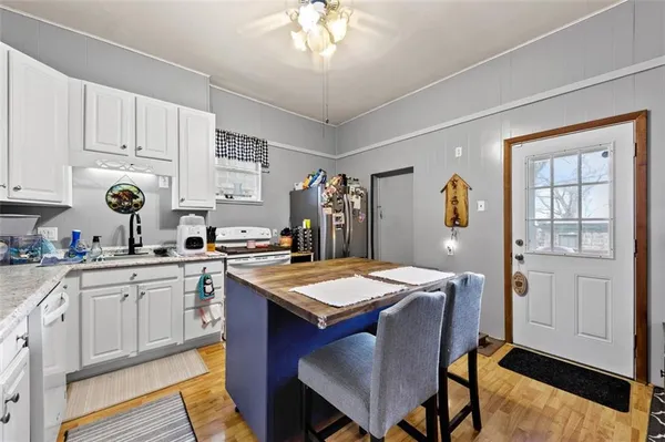a kitchen with stainless steel appliances granite countertop a sink dishwasher and white cabinets with wooden floor
