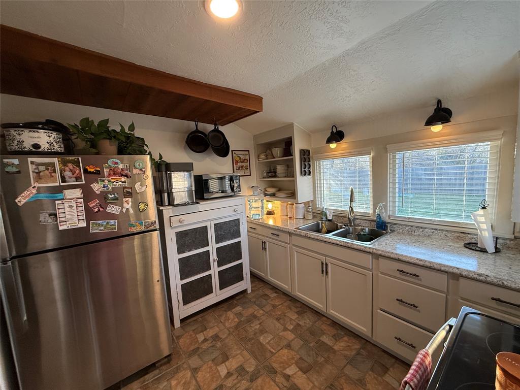 407 South Reagan Street Hamilton, TX 76531 - Photo 15 of 39 a kitchen with stainless steel appliances granite countertop a sink stove and refrigerator