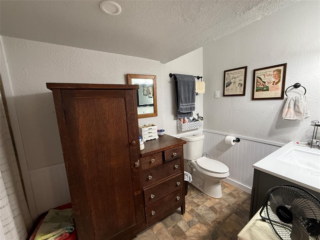 407 South Reagan Street Hamilton, TX 76531 - Photo 24 of 39 a bathroom with a toilet a sink a vanity and mirror