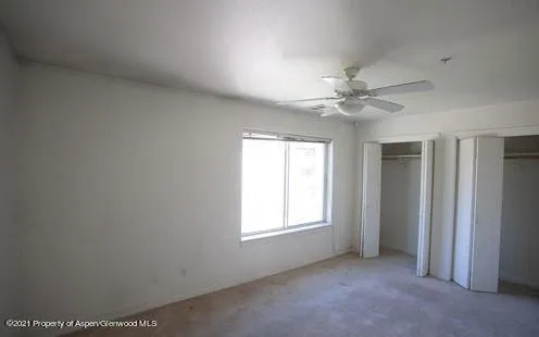 an empty room with windows and ceiling fan