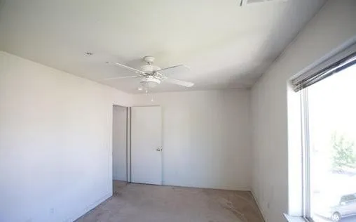 an empty room with windows and fan