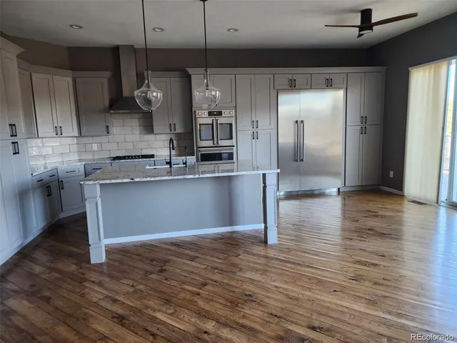 a kitchen with stainless steel appliances granite countertop a refrigerator a sink dishwasher a stove and a refrigerator