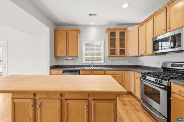 a kitchen with stainless steel appliances granite countertop a stove a sink and a microwave