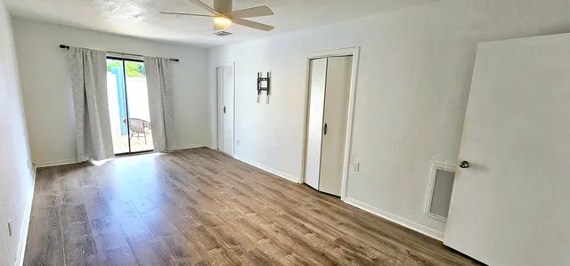 an empty room with wooden floor and a ceiling fan