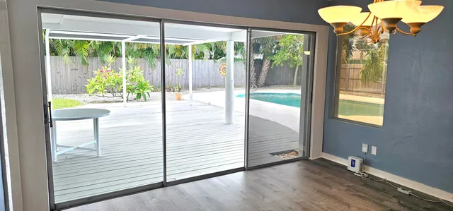 a view of an empty room with a window and wooden floor