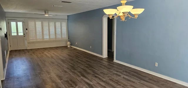 a view of a hallway with wooden floor and a chandelier