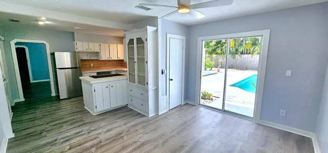 a view of a kitchen with wooden floor electronic appliances and windows