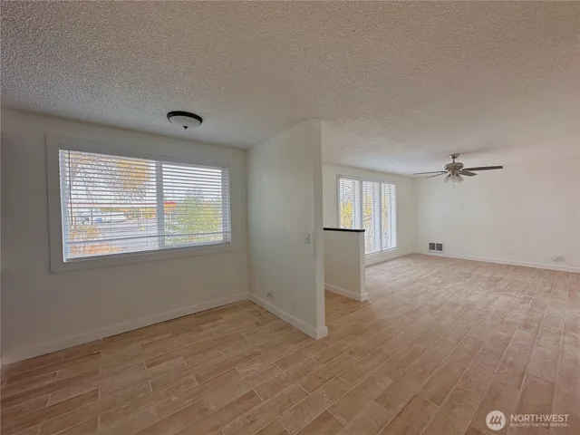 a view of empty room with wooden floor and fan