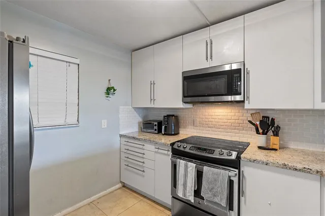 a kitchen with stainless steel appliances granite countertop white cabinets a stove top oven a sink and dishwasher