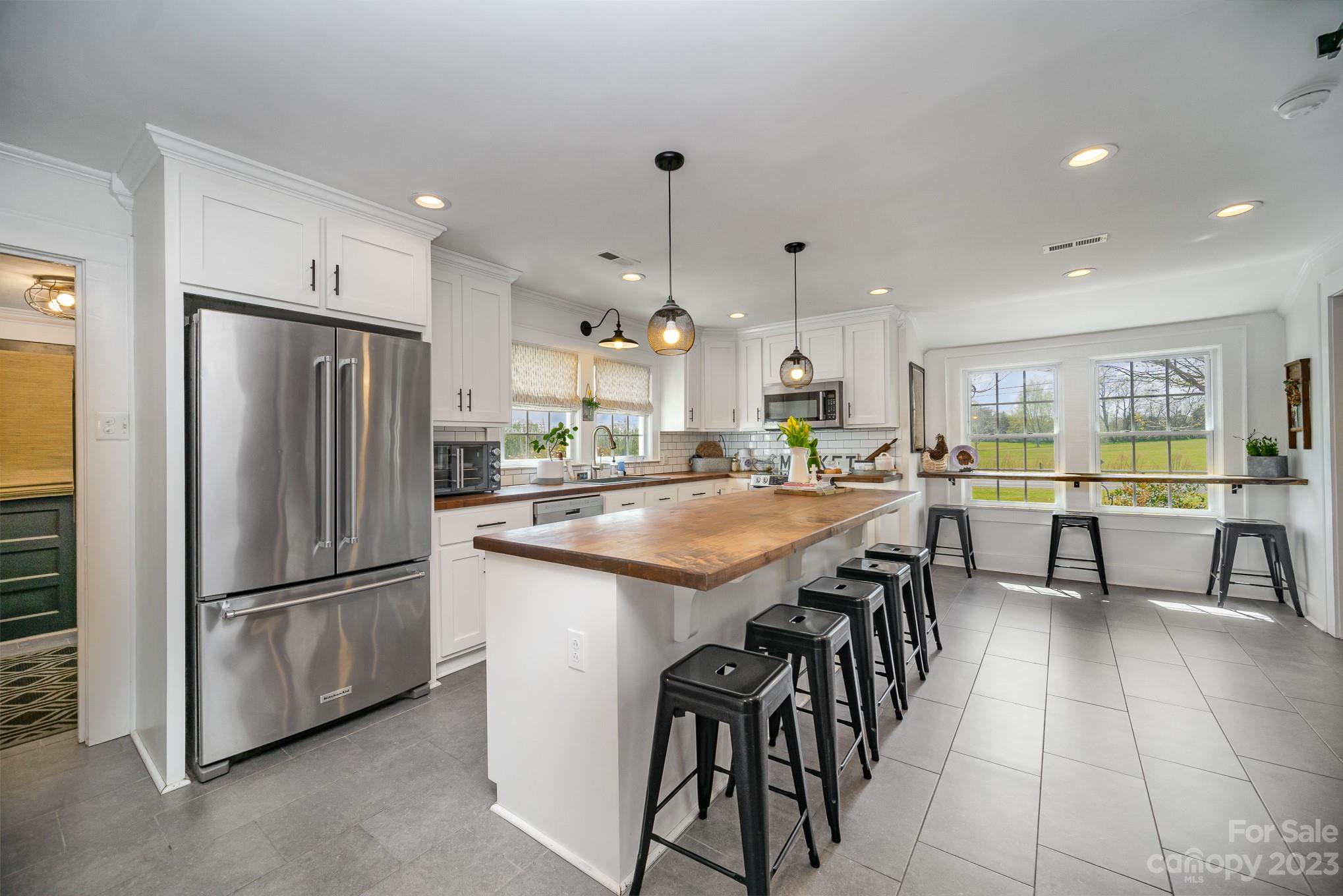 898 Hilltop Road Oakboro, NC 28129 - Photo 21 of 34 a kitchen with granite countertop a refrigerator a stove a sink a dining table and chairs
