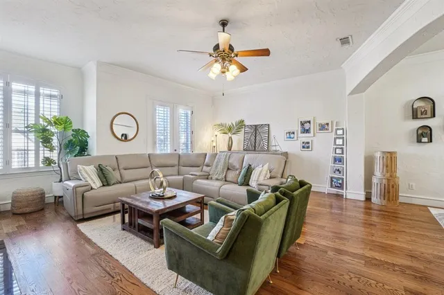 a living room with furniture a chandelier fan and wooden floor