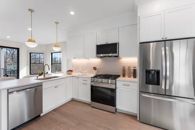 a kitchen with cabinets stainless steel appliances and wooden floor