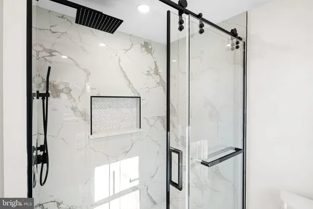 a bathroom with a glass shower door and mirror