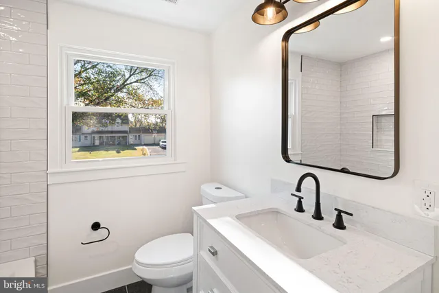 a bathroom with a granite countertop toilet a sink and mirror