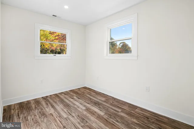 an empty room with wooden floor and window