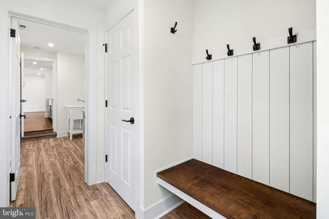 a view of a hallway with wooden floor and a bathroom