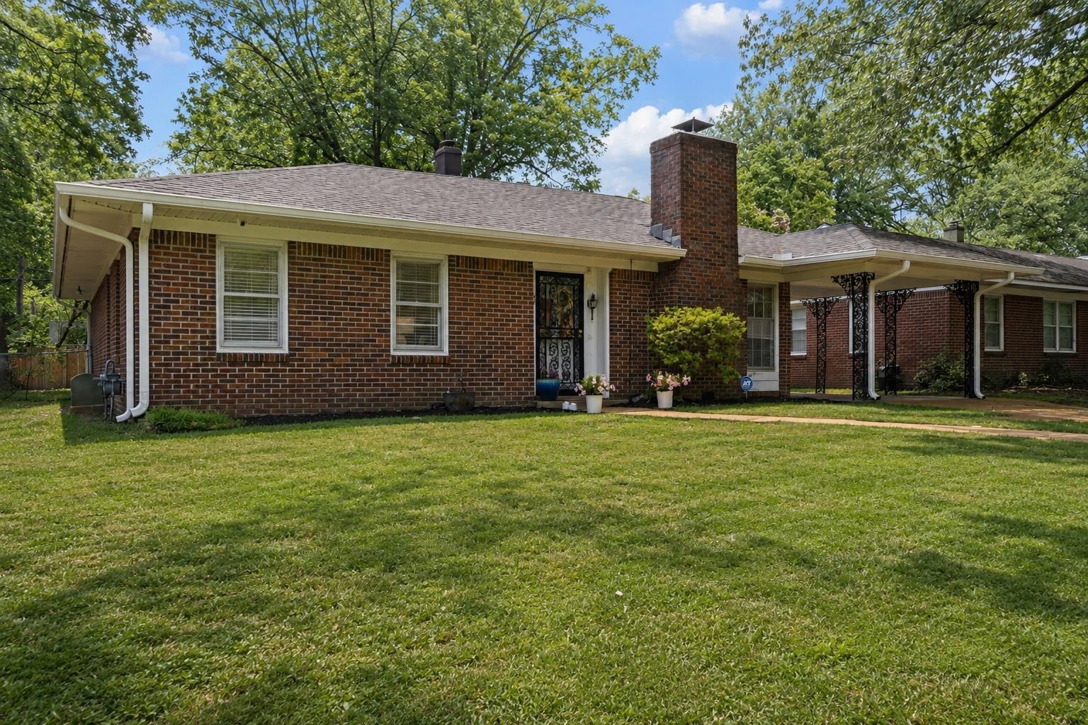 4491 Garnett Road Memphis, TN 38117 - Photo 3 of 32 Brick ranch-style home featuring a covered carport, prominent brick chimney, and a front entry with a storm door