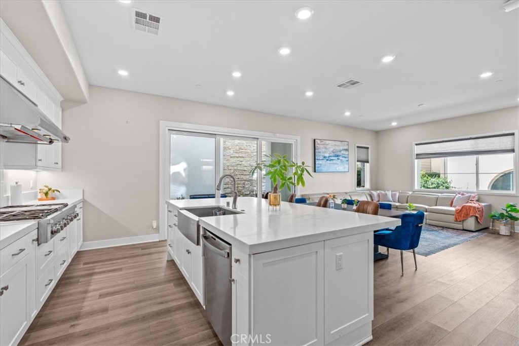 113 Source Irvine, CA 92618 - Photo 14 of 38 a large white kitchen with a stove a sink a refrigerator and a dining table with wooden floor