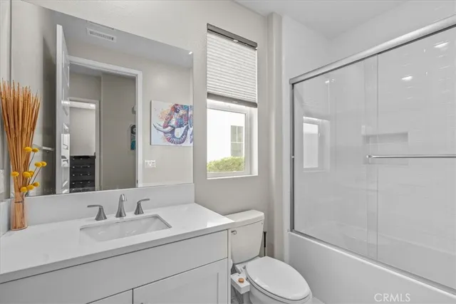 a bathroom with a granite countertop sink toilet a mirror and shower