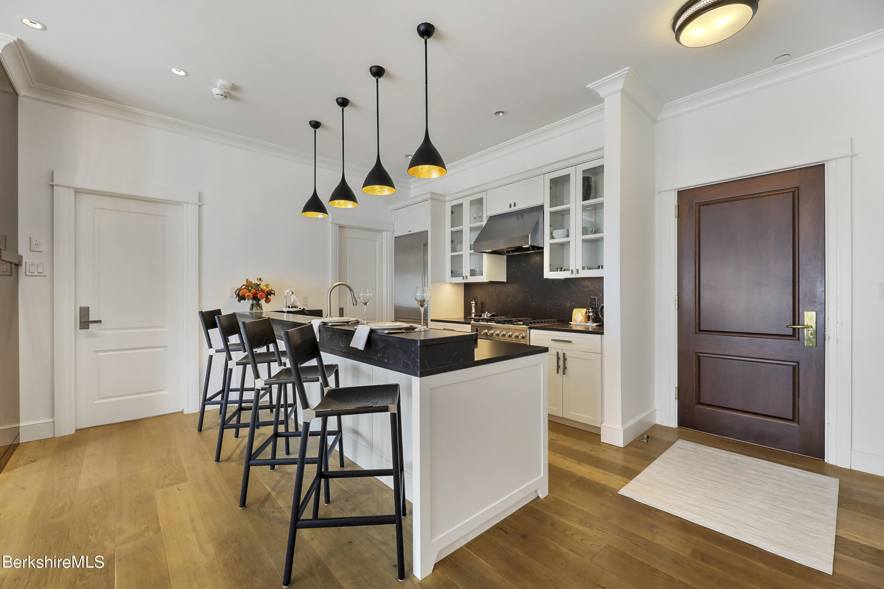 165 Kemble Street, Unit 16 Lenox, MA 01240 - Photo 12 of 31 a kitchen view with stainless steel appliances kitchen island granite countertop a table chairs in it and a wooden floor