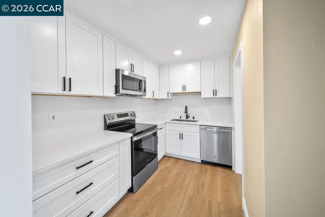 a kitchen with granite countertop white cabinets and stainless steel appliances