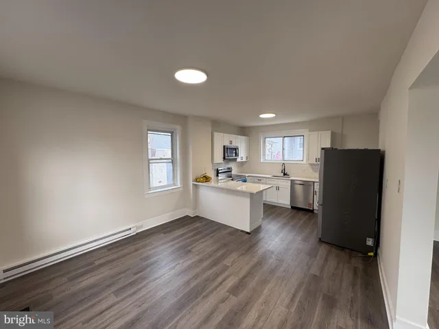 a large white kitchen with a refrigerator a sink dishwasher and a stove with wooden floor