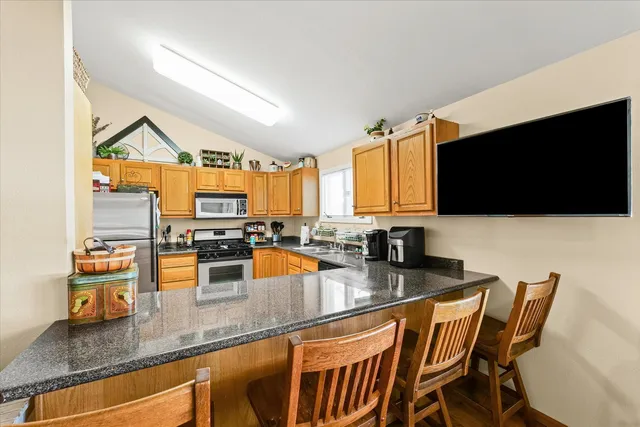 a kitchen with stainless steel appliances kitchen island granite countertop a table and chairs in it