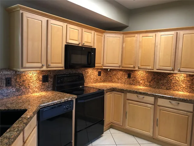 a kitchen with granite countertop cabinets stainless steel appliances a sink and a window