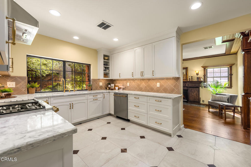 10484 Creek Road Oak View, CA 93022 - Photo 13 of 52 a kitchen with granite countertop a stove a sink and white cabinets with wooden floor