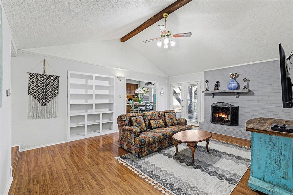 6013 Robin Drive Watauga, TX 76148 - Photo 19 of 30 Living room featuring a textured ceiling, a brick fireplace, wood finished floors, a ceiling fan, and built in features