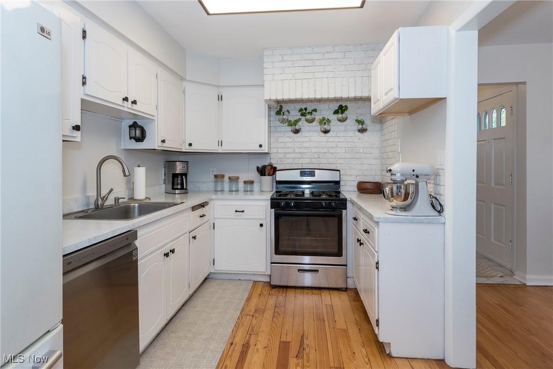 33716 Baldwin Road Solon, OH 44139 - Photo 12 of 40 Kitchen with appliances with stainless steel finishes, light wood-type flooring, sink, and white cabinets