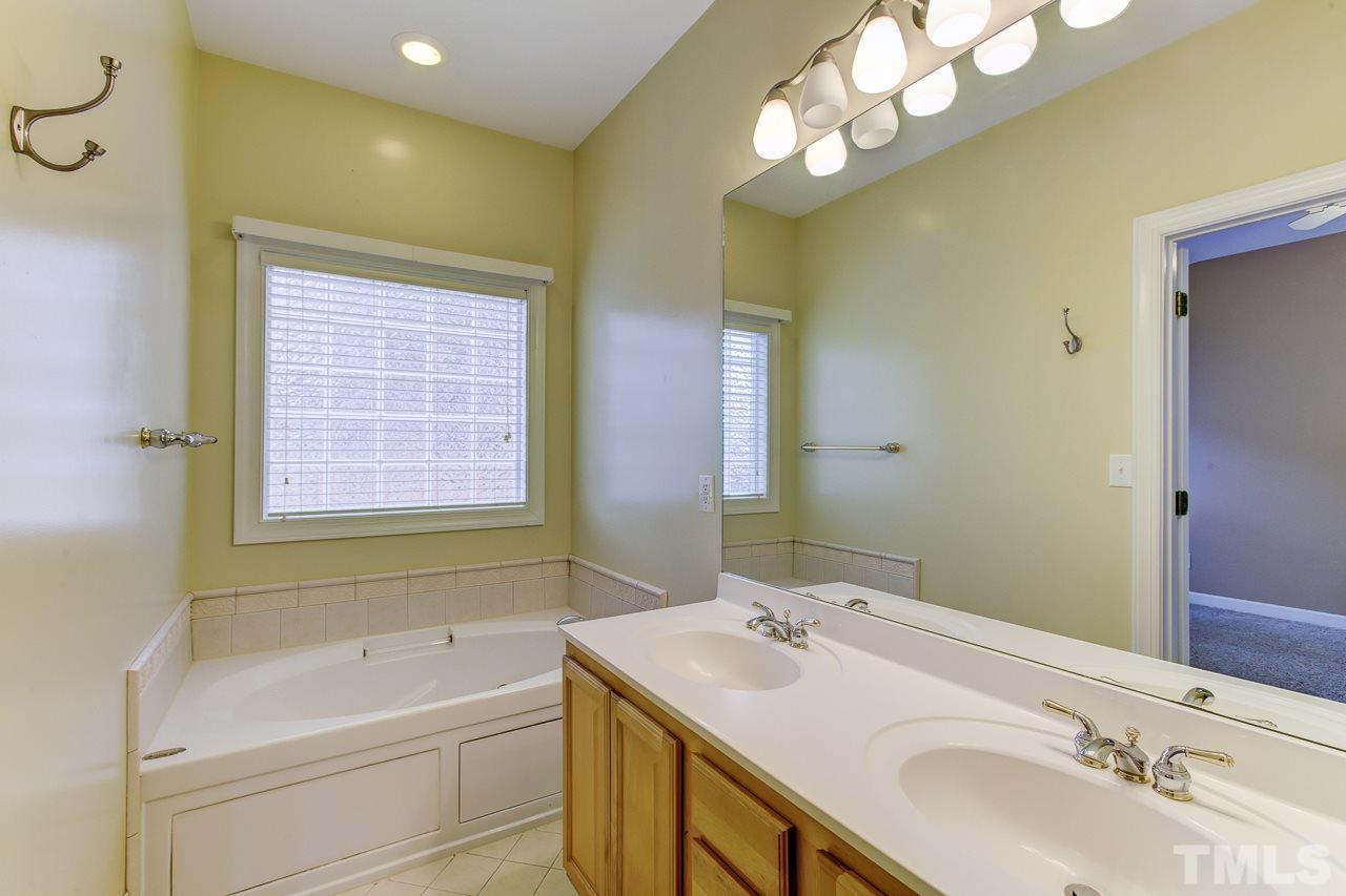 1432 Turner Farms Road Garner, NC 27529 - Photo 15 of 25 a bathroom with a sink a large mirror and a bathtub with shower