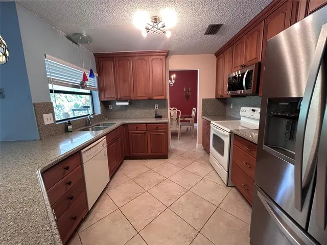 a large kitchen with stainless steel appliances wooden cabinets a stove top oven a sink and dishwasher