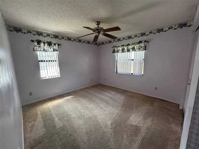 en empty room with windows and ceiling fan