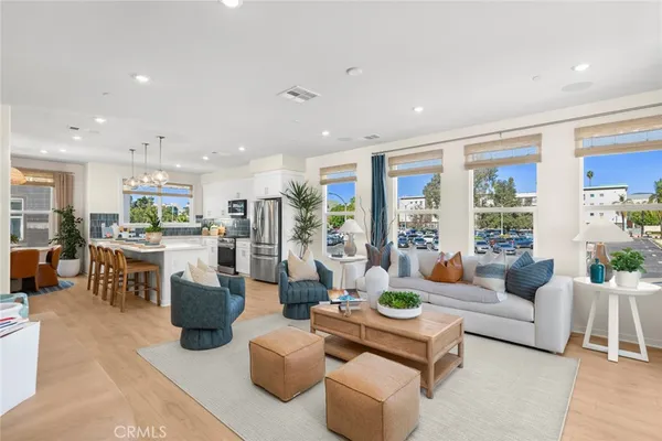 a living room with furniture kitchen view and large windows