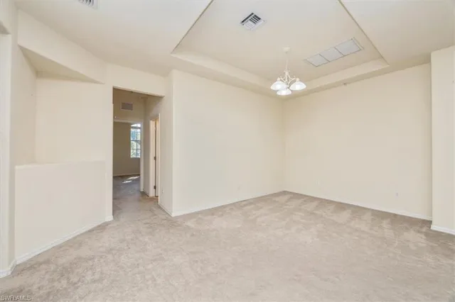 an empty room with a chandelier fan and closet area
