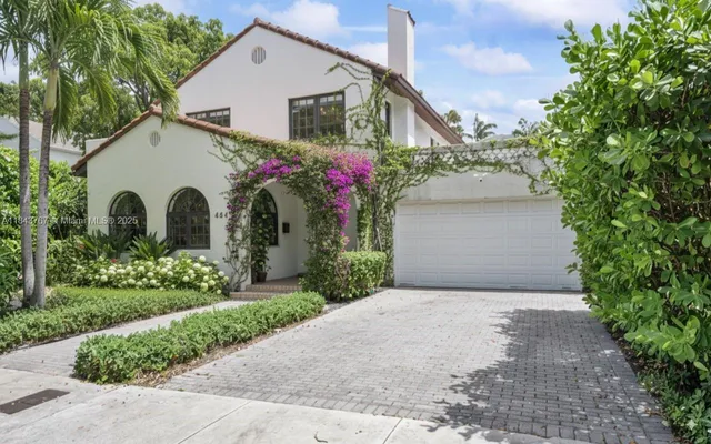 a view of a white house with a yard and potted plants