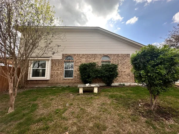 a backyard of a house with potted plants and large tree