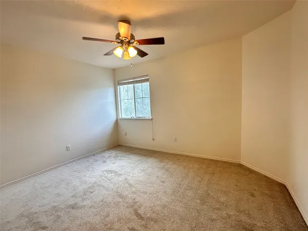 an empty room with a window and a chandelier fan