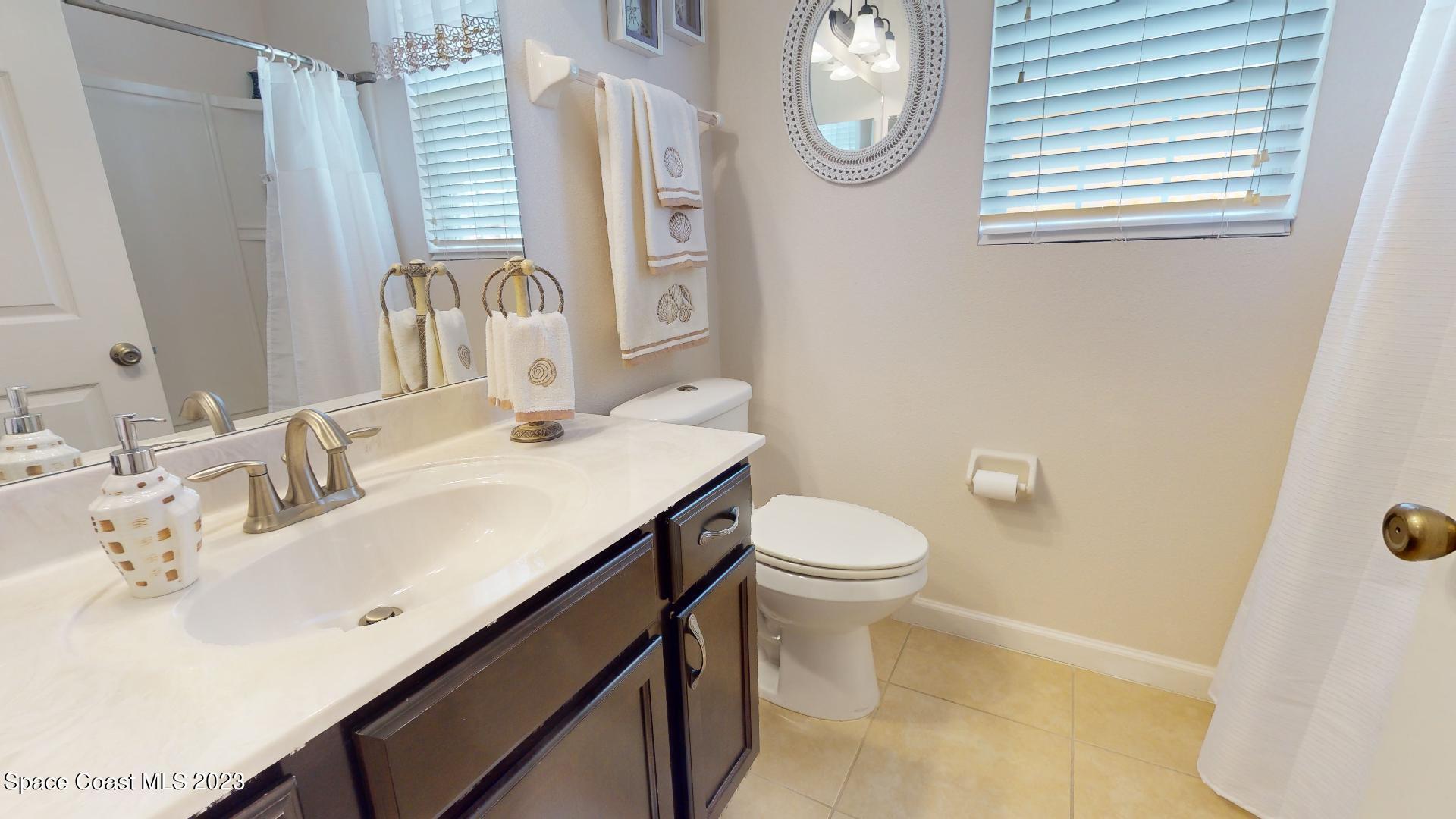 3242 Arden Circle Melbourne, FL 32934 - Photo 21 of 28 a bathroom with a sink a toilet and a mirror