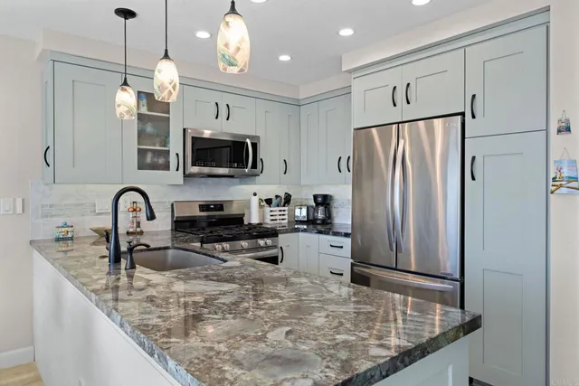 a kitchen with stainless steel appliances granite countertop a refrigerator a stove top oven a sink and dishwasher