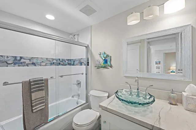 a bathroom with a granite countertop sink a toilet and shower