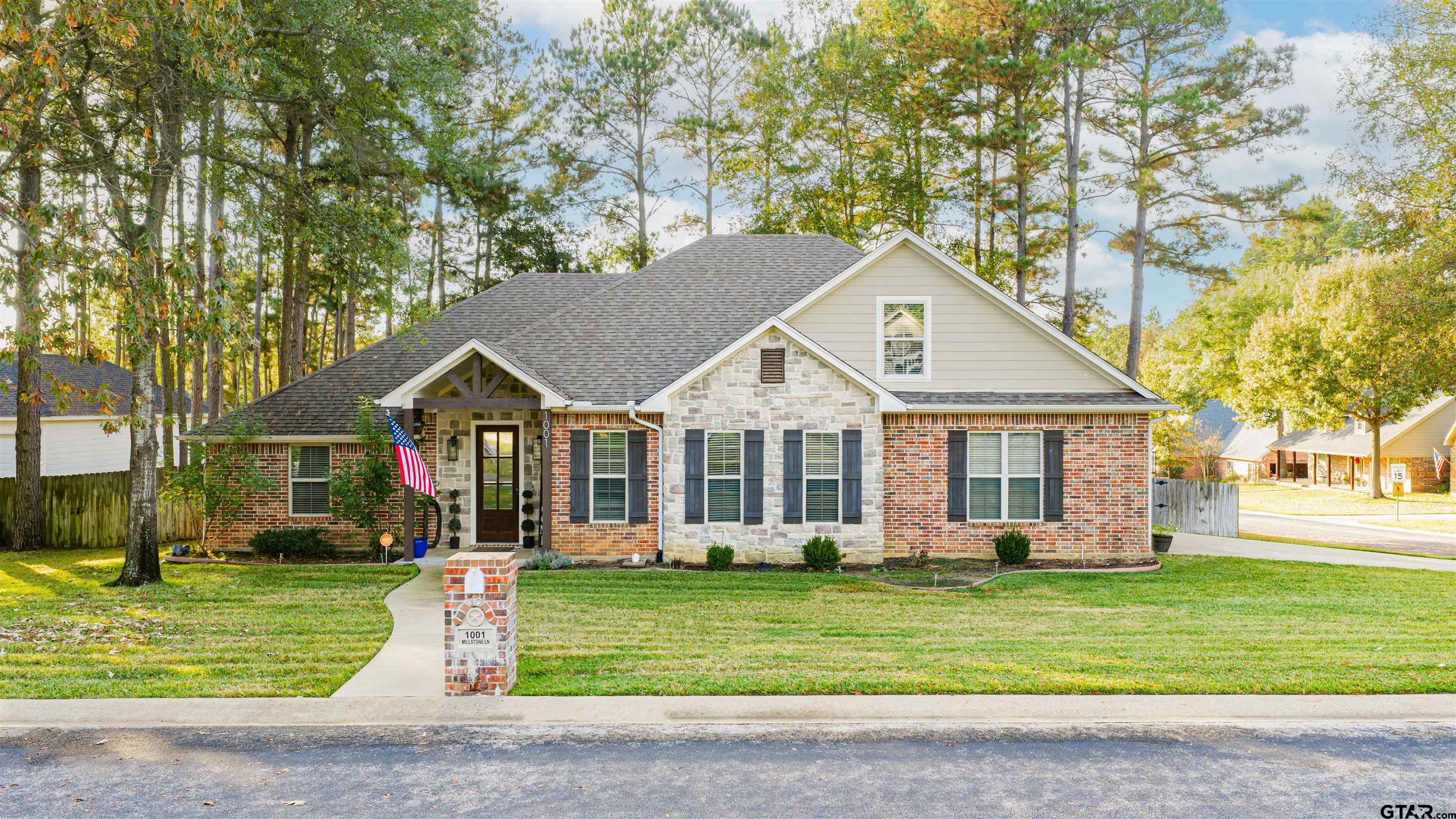 a front view of a house with a garden and trees
