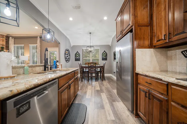 a kitchen with stainless steel appliances granite countertop a sink a stove and a wooden floors