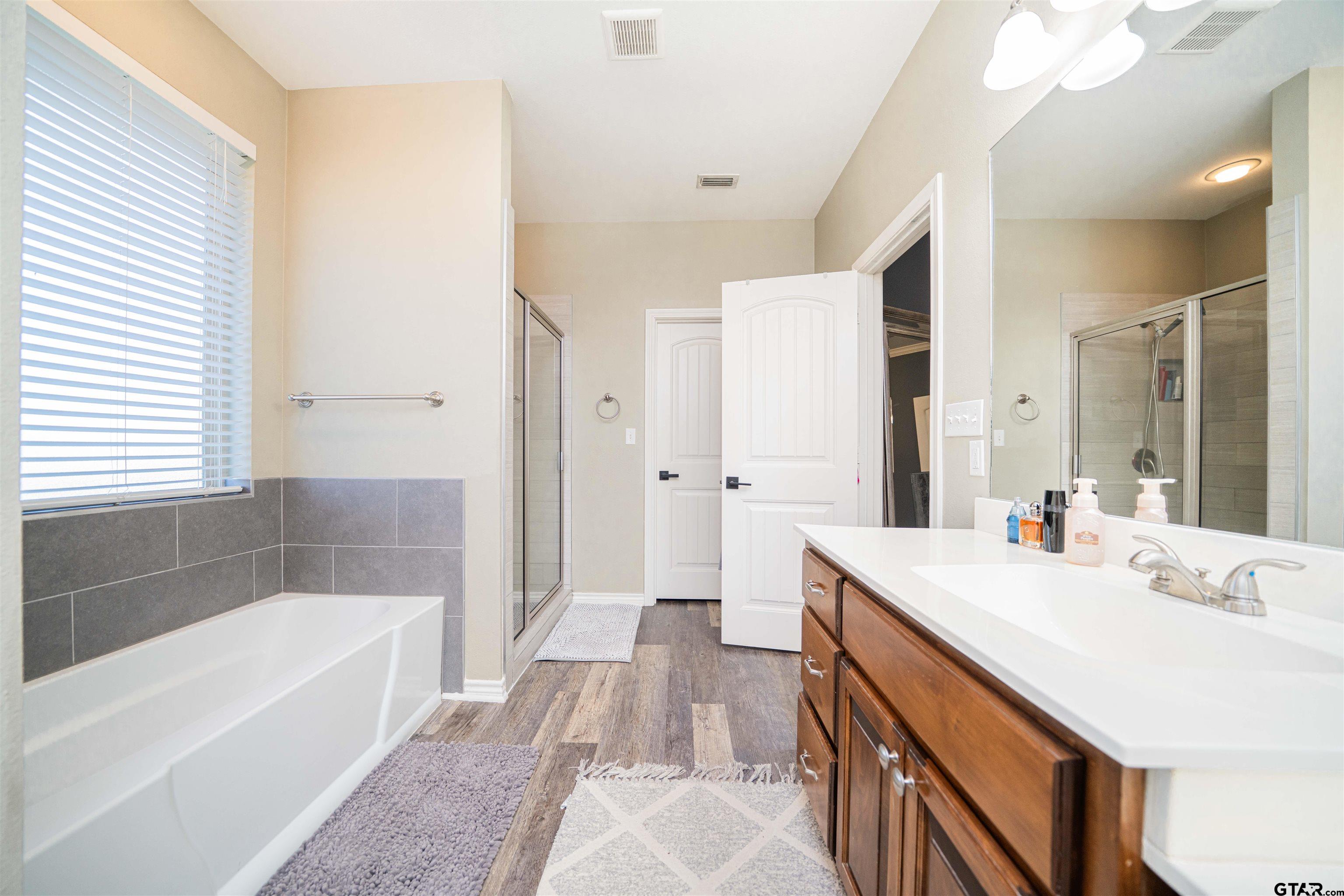 1001 Millstone Lane Chandler, TX 75758 - Photo 16 of 30 a bathroom with a bathtub a sink a mirror and a shower